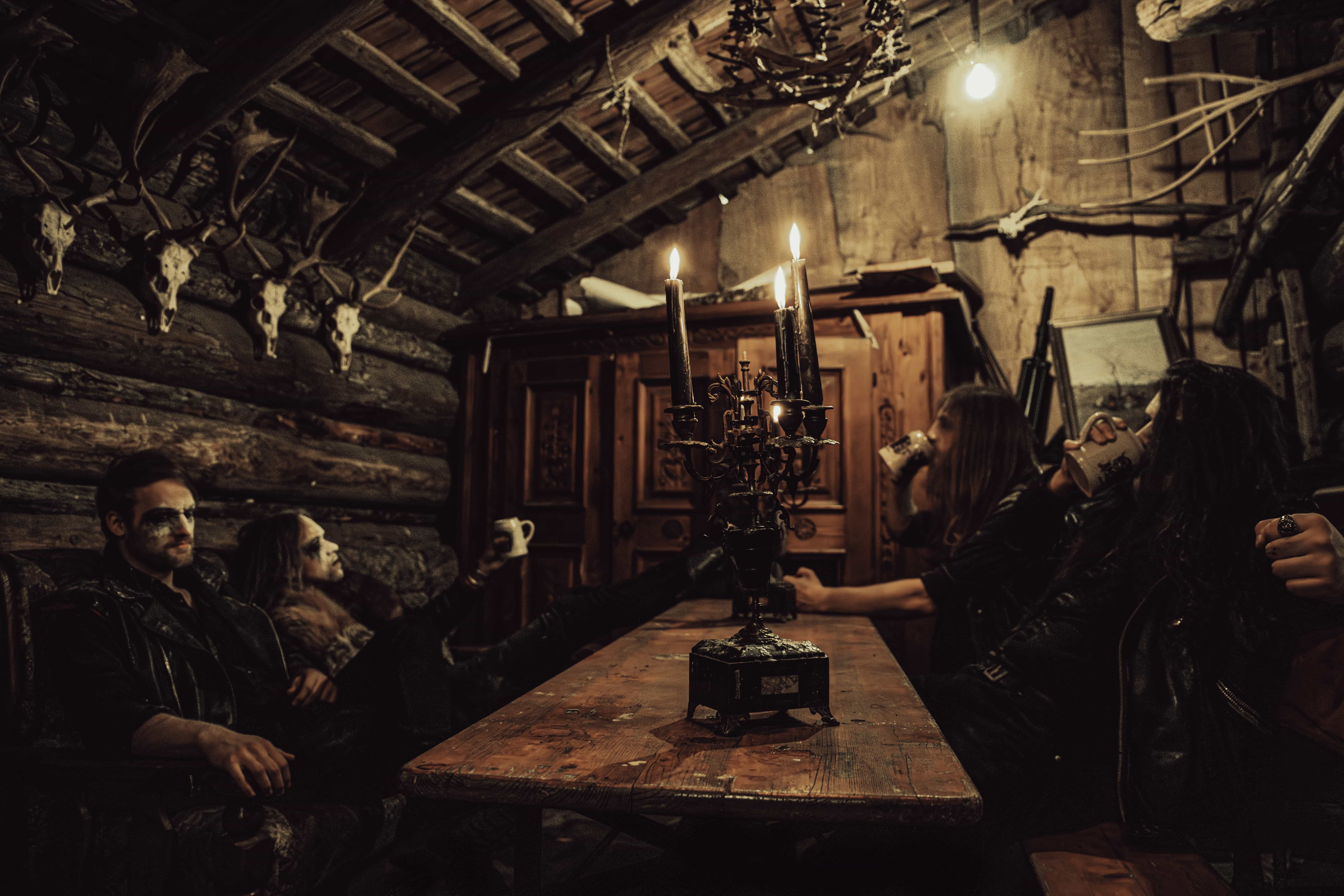Ensanguinate band sitting behind table drinking, hunting horns, Abtenau photoshoot